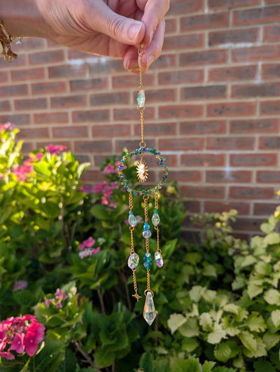A sun catcher hanging by a brick wall