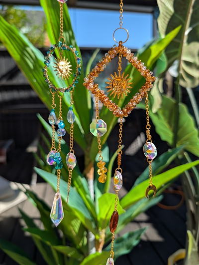 Two beaded sun catchers with golden sun charms, hanging outdoors