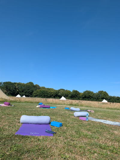 Yoga mats and bolsters laid out on the grass